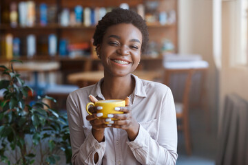 Happy African American woman having coffee in cafe