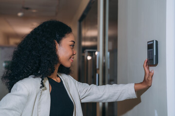 A face scanner being used by a woman to open a door at an office building. Control device for Security system. Device to control a security system..