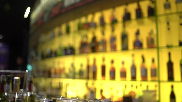 Blurred blurred background with bartender putting bottles on drink bottle rack in bar.