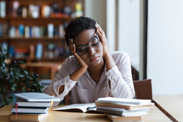 Tired African American woman studying for exam in coffee shop