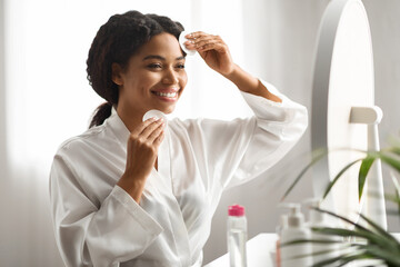 Black Woman Using Cotton Pads, Cleaning Face With Micellar Water At Home