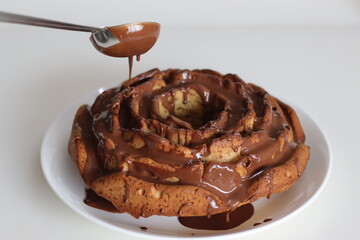 Rose flower shaped whole wheat plantain cake topped with chocolate sauce.