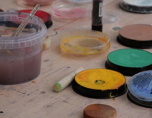 peintures et autres accessoires d'un atelier de grimage pour enfants, déposés sur une table en bois