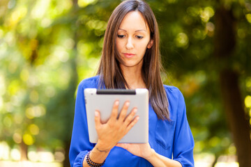 Fototapeta premium Young woman using a digital tablet in the park and enjoying the freedom of rhe wireless internet connection