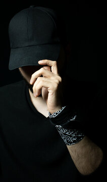 Man standing alone in the dark wearing a black hoodie and hat