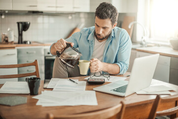 Fototapeta premium Young man going over his home finances in the kitchen