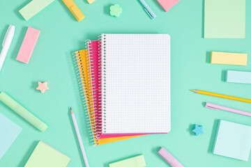 Back to school background. Flat lay, top view of school accessories, notebook, pens on isolated light green table background. School stationery on desk. Copyspace