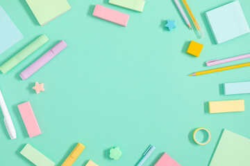Back to school background. Flat lay, top view of colorful scattered stationery on isolated light green table background. School supplies on desk. Copyspace.