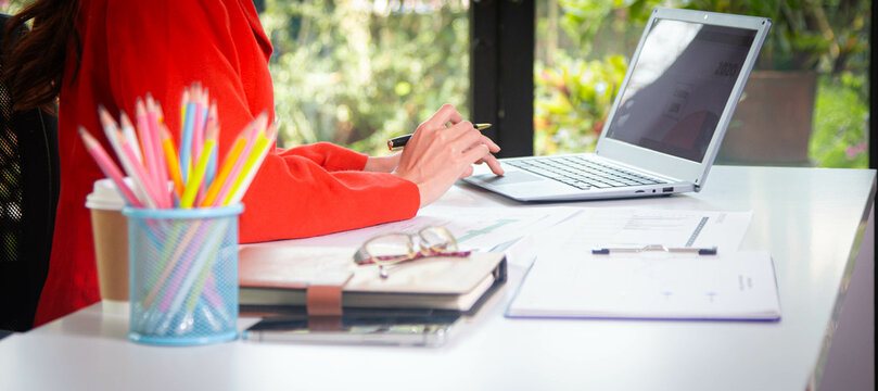 Businesswoman searching through laptop for online real estate on office desk