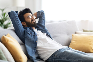 Obraz premium Domestic Rest. Young Handsome Indian Guy Leaning Back On Couch At Home