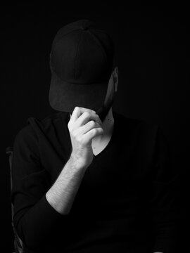 faceless man wearing black hiding behind a cat 
