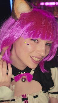 Vertical of young female blogger wearing cat maid cosplay outfit and accessories demonstrating her contour powder, mascara and lip gloss on camera