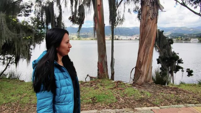 Young woman walking in long dress at summer nature near lake river.
