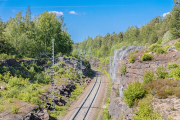 Fototapeta na wymiar single-track railway passing among the rocks overgrown with forest