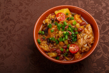 hot cholent sprinkled with green onions in a clay plate on the table