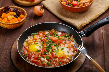 Jewish food hot cholent and shakshuka in a frying pan on a set Shabbat table.