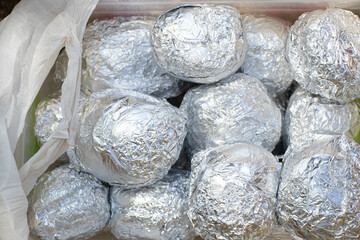 Bake potatoes in foil on the grill in the coals in the summer at a picnic, food