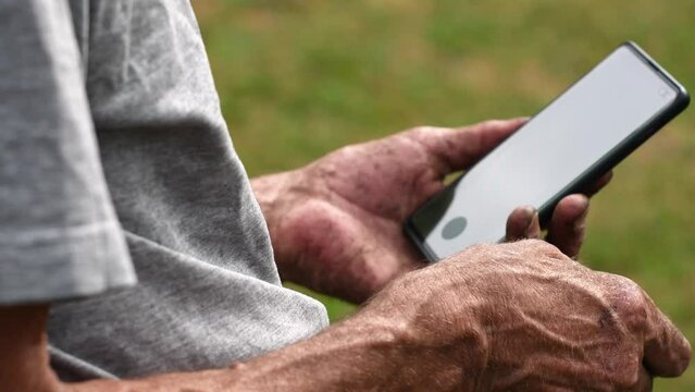 man with dirty hands holds a cell phone with a green screen in his hands