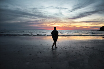 Man walking alone on the beach in Thailand
