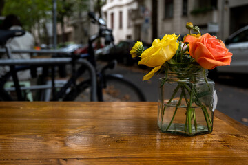 a vase with roses on a table of a cafe, usable as background
