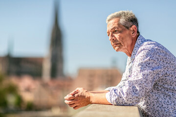 Urban lifestyle and traveling: Portrait of an elderly best ager man posing in a city at a sunny day...