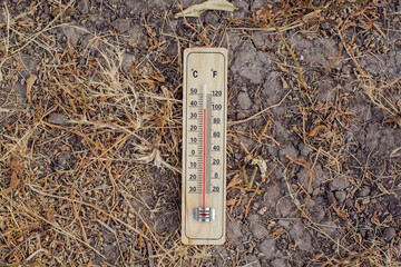 Hot weather. Thermometer in hand in front of an urban scene during heatwave. High temperature...