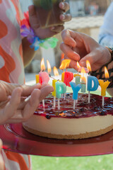 Caucasian hands lighting candles on a birthday cake.