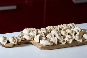 raw gyoza, before cooking, on a wooden board. close-up view in the kitchen