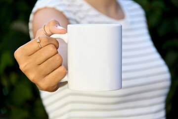 Girl is holding white mug in hands. Blank 11 oz ceramic cup
