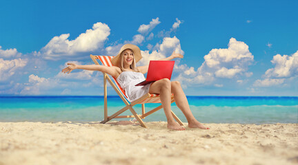 Young woman sitting on a beach chair with a laptop computer