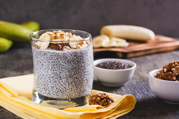 Delicious breakfast chia seeds with banana and walnuts in a glass on the table