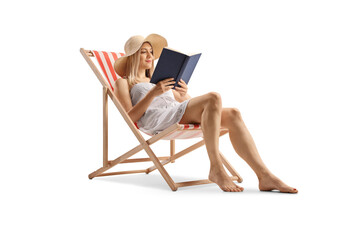 Beautiful young woman in a white dress sitting on a beach chair and reading a book