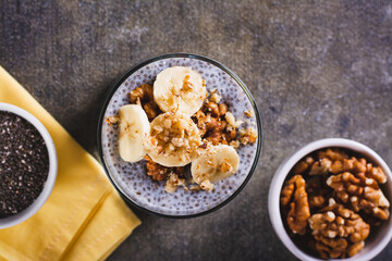 Close up of delicious breakfast chia seeds with banana and walnuts in a glass on the table top view