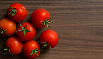 Fresh tomatoes in plate on dark wooden background, harvest tomatoes, top view. Free space