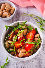 Homemade salad of white beans, cherry tomatoes and arugula in a bowl vertical view