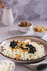 Soft cottage cheese with blackcurrant and walnuts on a breakfast plate vertical view