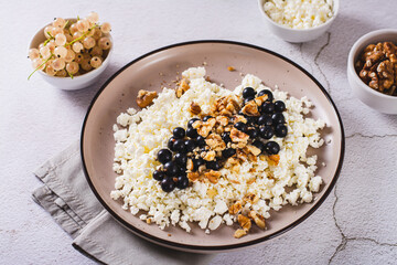 Homemade cottage cheese with fresh blackcurrants and walnuts on a plate