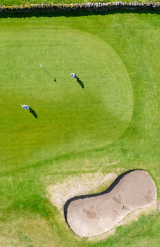 Golf course green aerial view and two players
