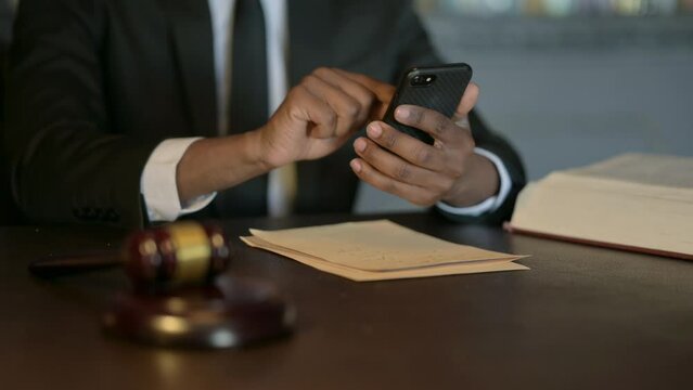 Close Up of African Judge using Smartphone in Court
