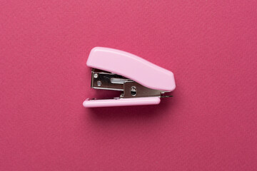 Pink stapler on color backgroung, top view - obrazy, fototapety, plakaty