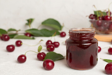 Jar with tasty homemade cherry jam on wooden table