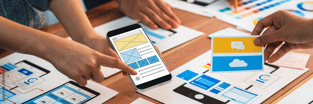 Poster Panorama shot of front-end developer team brainstorming UI and UX designs for mobile app on paper wireframe interface. User interface development team planning for user-friendly UI design. Scrutinize