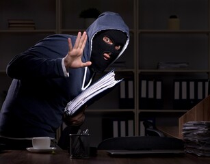 Male thief in balaclava in the office night time