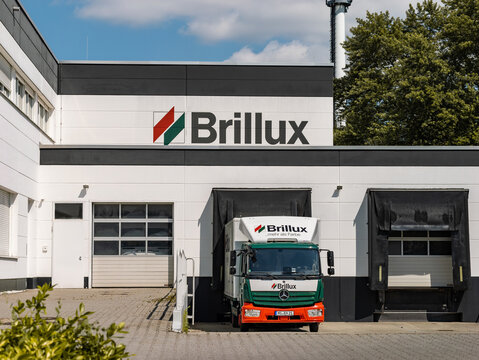 DRESDEN, GERMANY - 24. June 2023: Brillux logo sign on a building and a truck. The vehicle is in the loading zone of the store building. The German family business sells paint and related products.