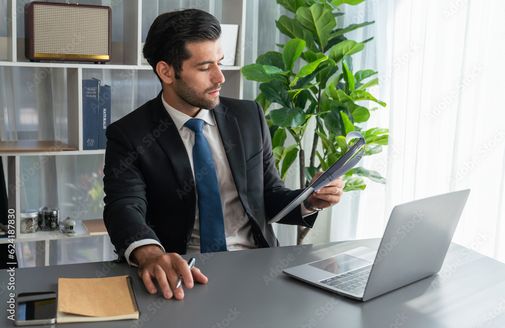 Poster modern professional businessman at modern office desk using laptop to work and write notes. diligent