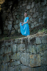 A woman in a blue dress stands in the ruins of a medieval fortress.