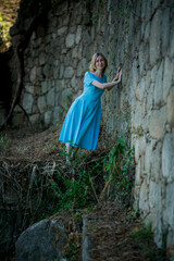 A woman in a blue dress makes her way through ancient ruins.