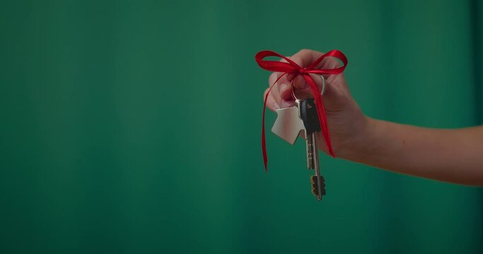 closeup view of keys from new home in female hand in green background, new flat as gift, 4K, Prores,
