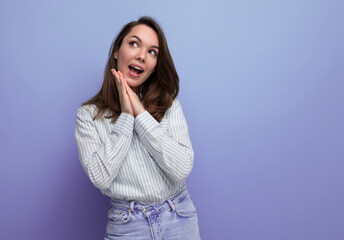dreamy 25s woman with dark hair in casual clothes on purple studio background with copy space