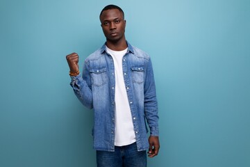 portrait of young smart inspired with dark skin american guy dressed stylishly in casual clothes on blue background with copy space